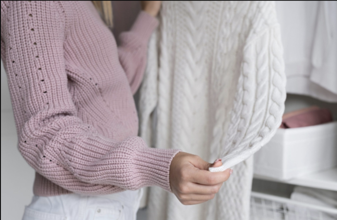 Close-up of cable knit sweaters in pink and cream showcasing craftsmanship